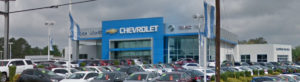 A large chevrolet dealership with lots of cars parked in front.