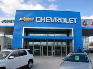 A chevrolet dealership with cars parked in front of it.