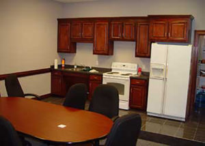 A kitchen with brown cabinets and black chairs.
