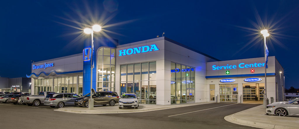A honda dealership at night with the lights on.