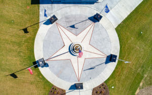 A star shaped concrete area with flags and speakers.