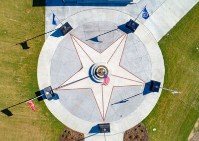 A star shaped concrete area with flags and speakers.