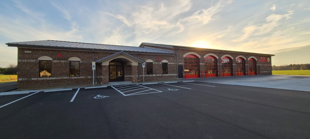 A fire station with red doors and a parking lot.