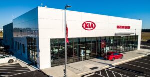 A kia dealership with cars parked outside.